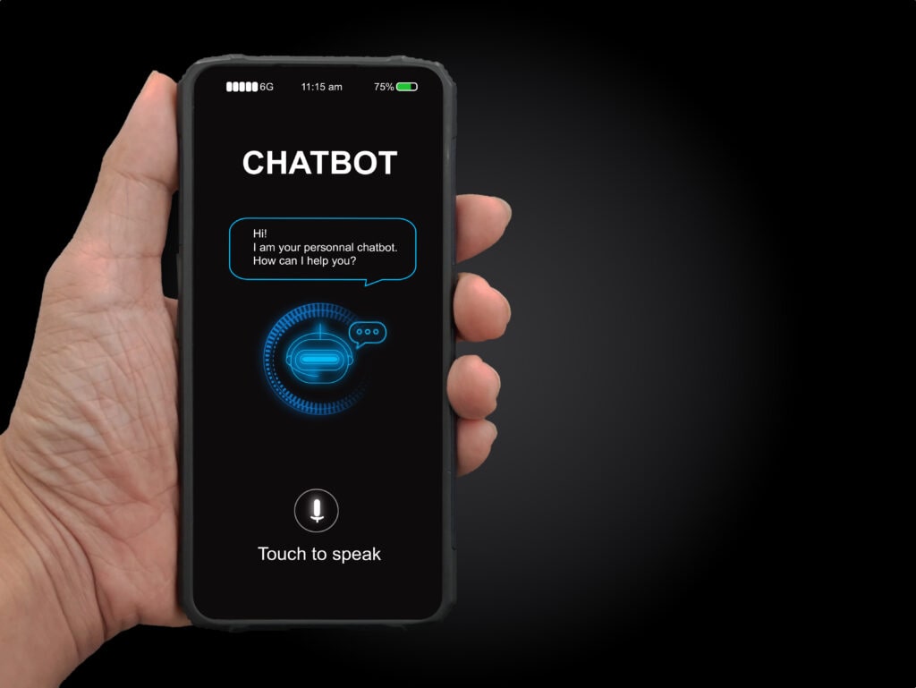 Man's Hand Holding A Mobile Smartphone Displaying A Chat Interface, Illustrating The Comparison Between Phone Answering Services And Chatbots.
