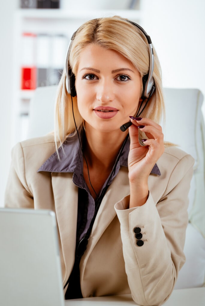 Professional Receptionist From Ruby Receptionist Providing Answering Services, Pictured At Her Desk With Headset On.