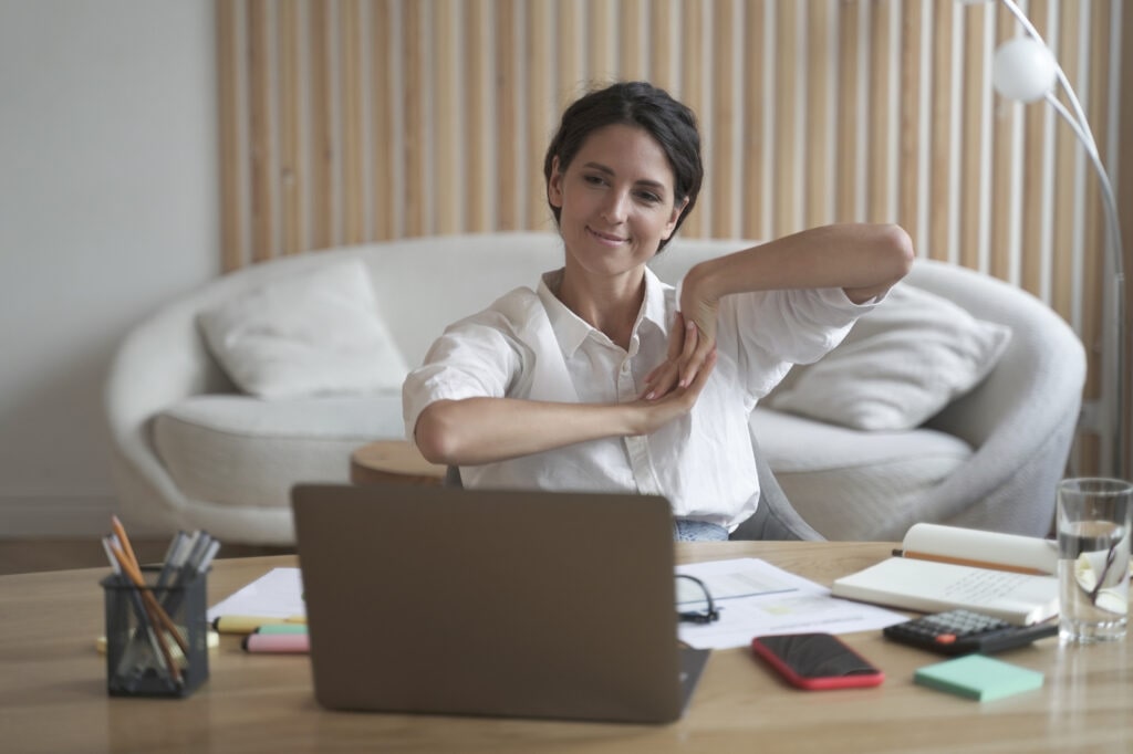 Positive Business Woman Doing Hands Stretching Exercises While Listening To Training Lectures Online